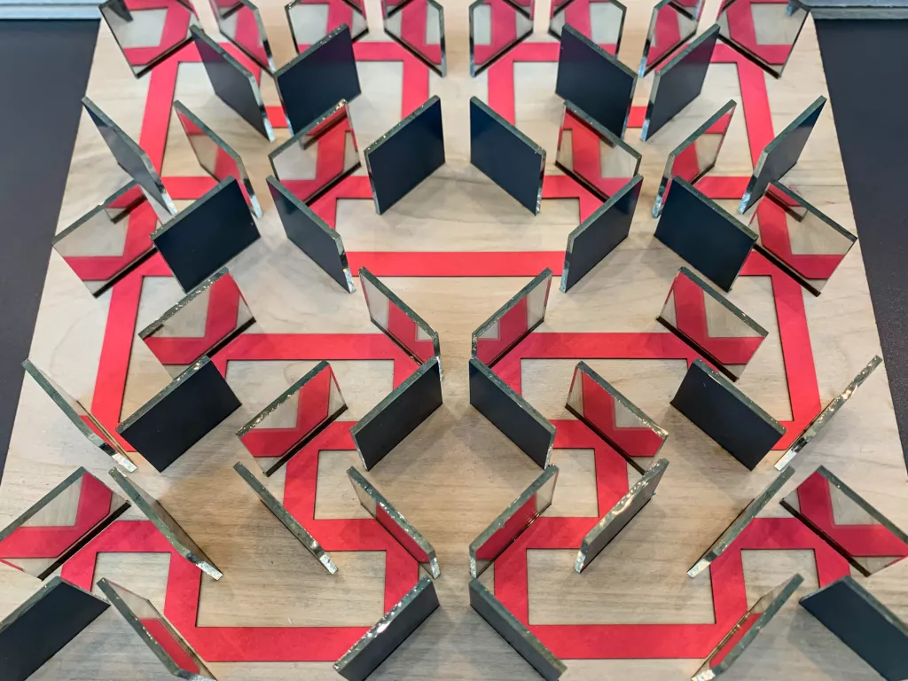 The labyrinth is made of different parts: The base is made of two pieces of wood glued together, where the top layer has slits precisely cut to hold the 52 mirrors in such a way that the back sides of the mirrors were on the appropriate diagonals.